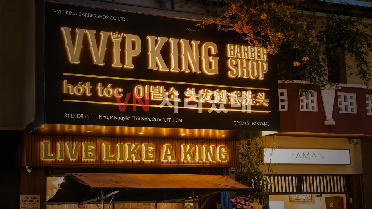 호치민 VVIP 킹 이발소 골드 왕관 조명 간판과 LIVE LIKE A KING 슬로건이 보이는 외관 야간 전경