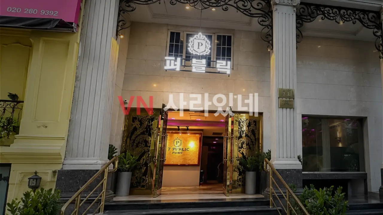 호치민 퍼블릭 가라오케 7군 유럽풍 석조 외관 — 한글 퍼블릭 간판·금색 데코 입구·항아리 화분 건물